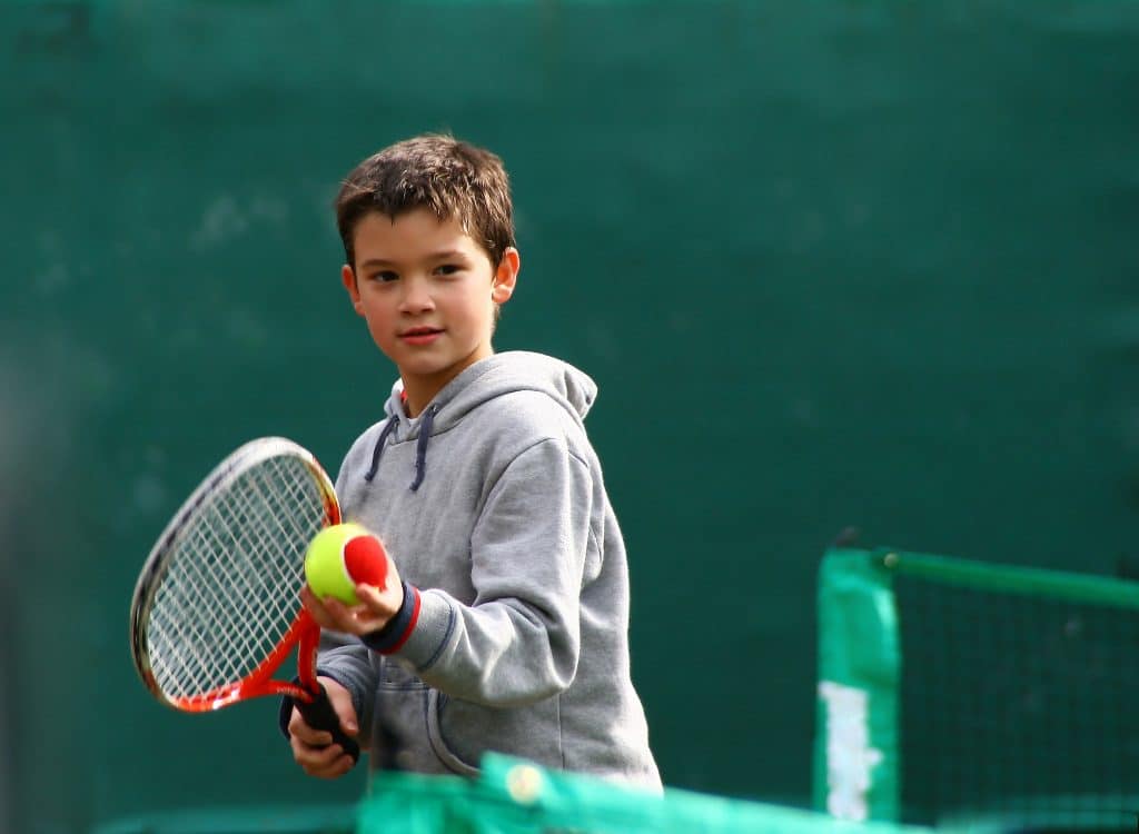 Boy preparing to serve red ball with racquet