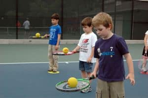 three boys balancing foam balls on tennis racquets