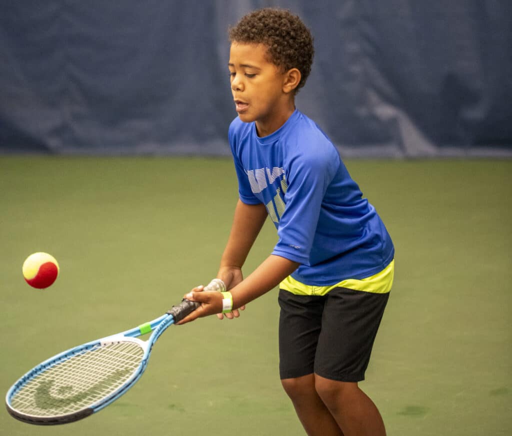 boy bouncing a ball on tennis racquet