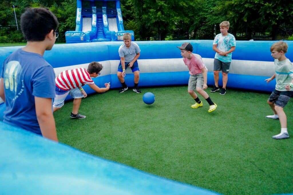 a group of boys playing in the inflatable gag pit at summer camp