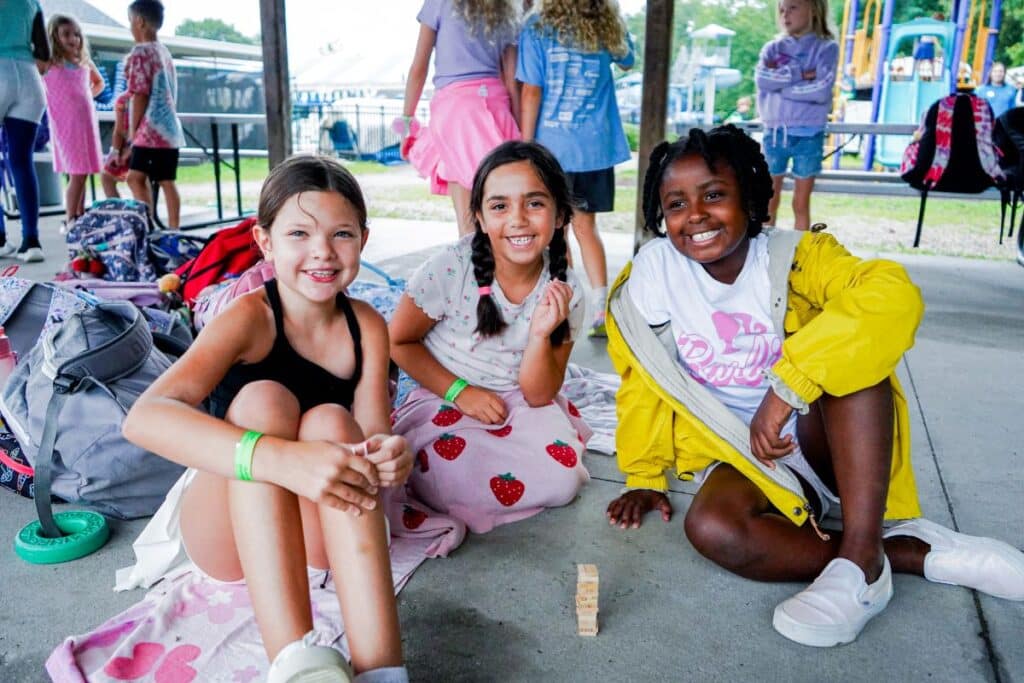 three girls at camp sitting and playing games