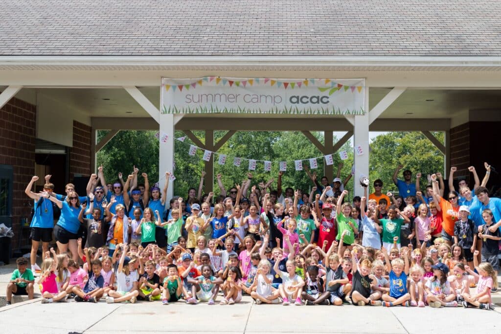 group photo of summer campers and counselors under the outdoor acac summer camp banner