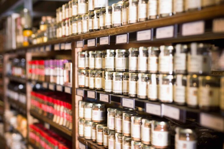 Shelves filled with glass jars of spices and seasonings arranged in rows at a store.